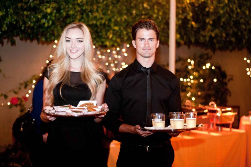 catering models serving food and drinks while wearing sleek black uniforms
